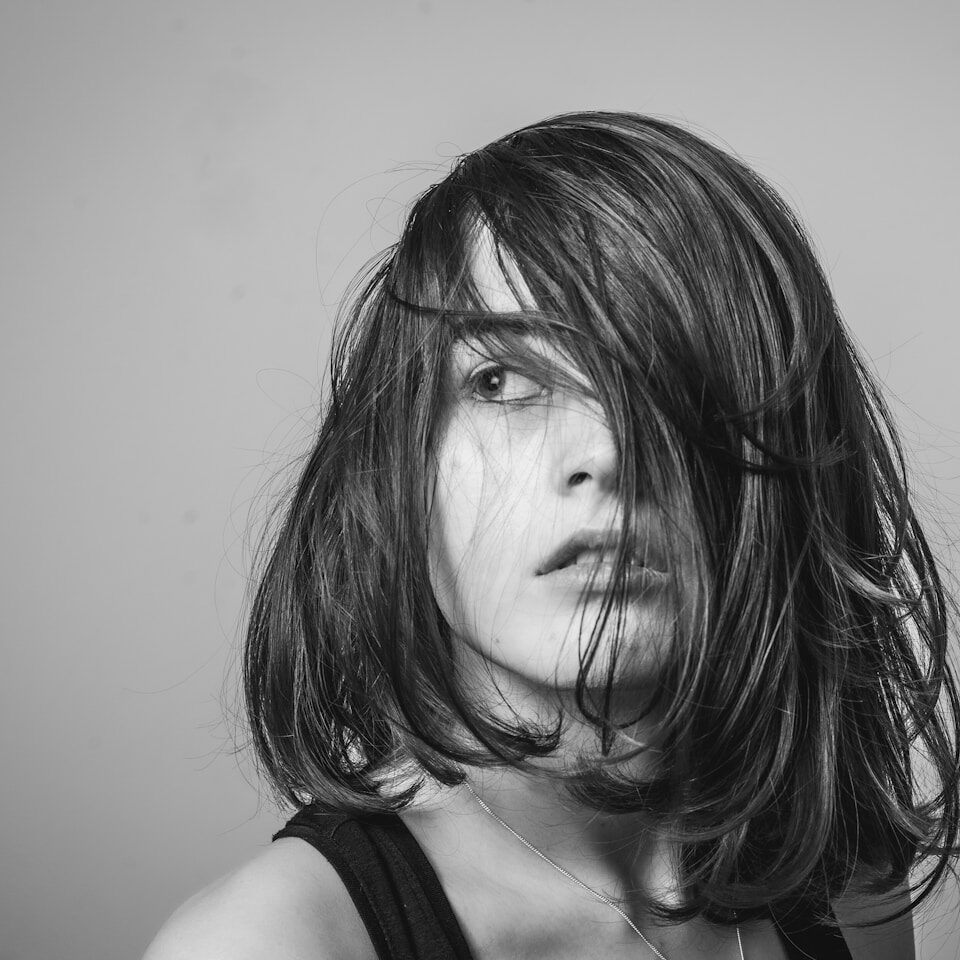 a black and white photo of a woman with her hair blowing in the wind