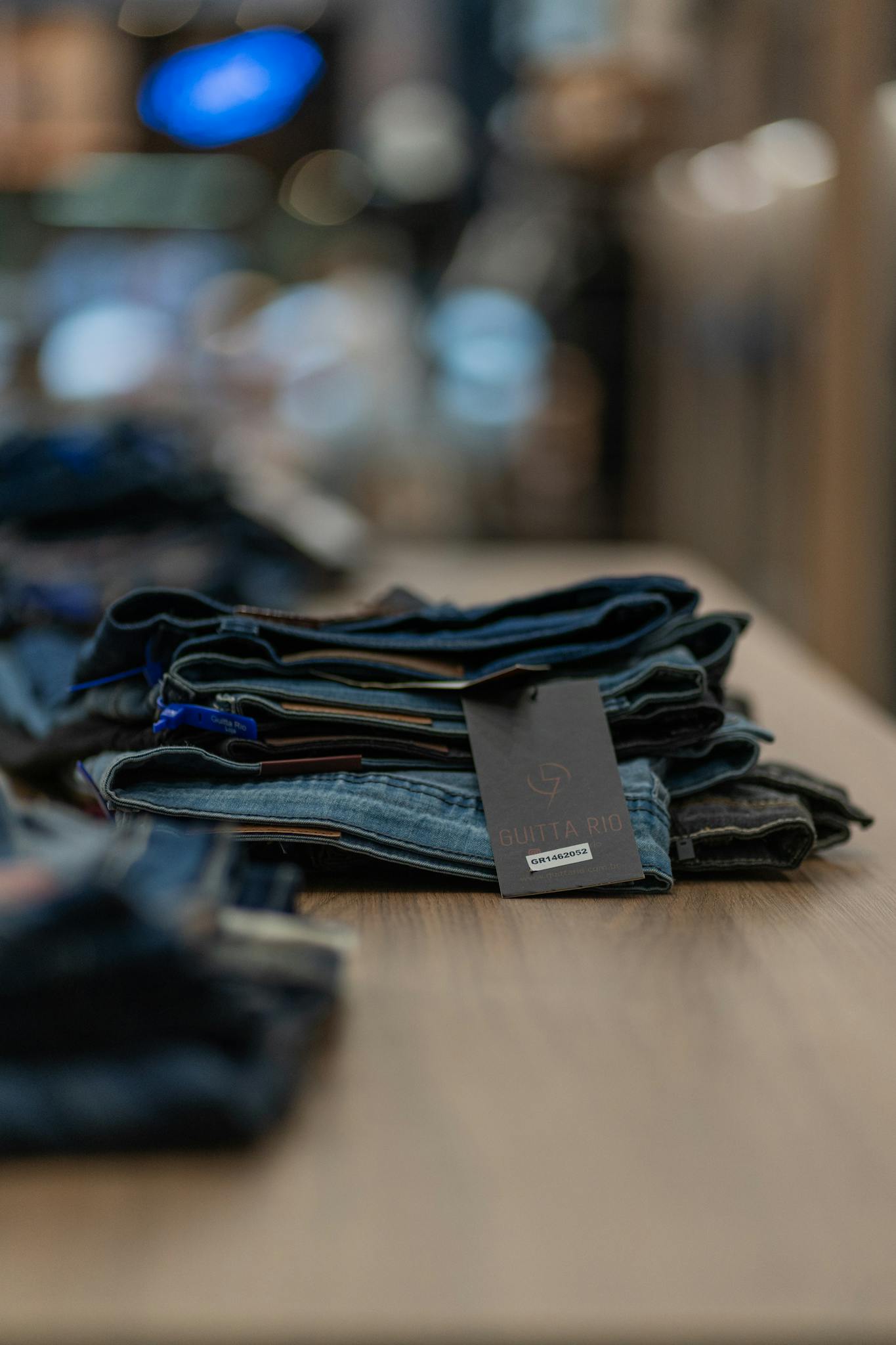 Close-up of folded jeans on a wooden table in a retail store, showcasing fashion and retail details.