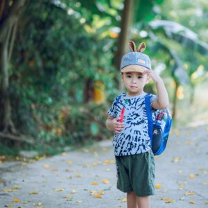Adorable young boy with backpack enjoying a summer day outdoors, exuding joy and innocence.