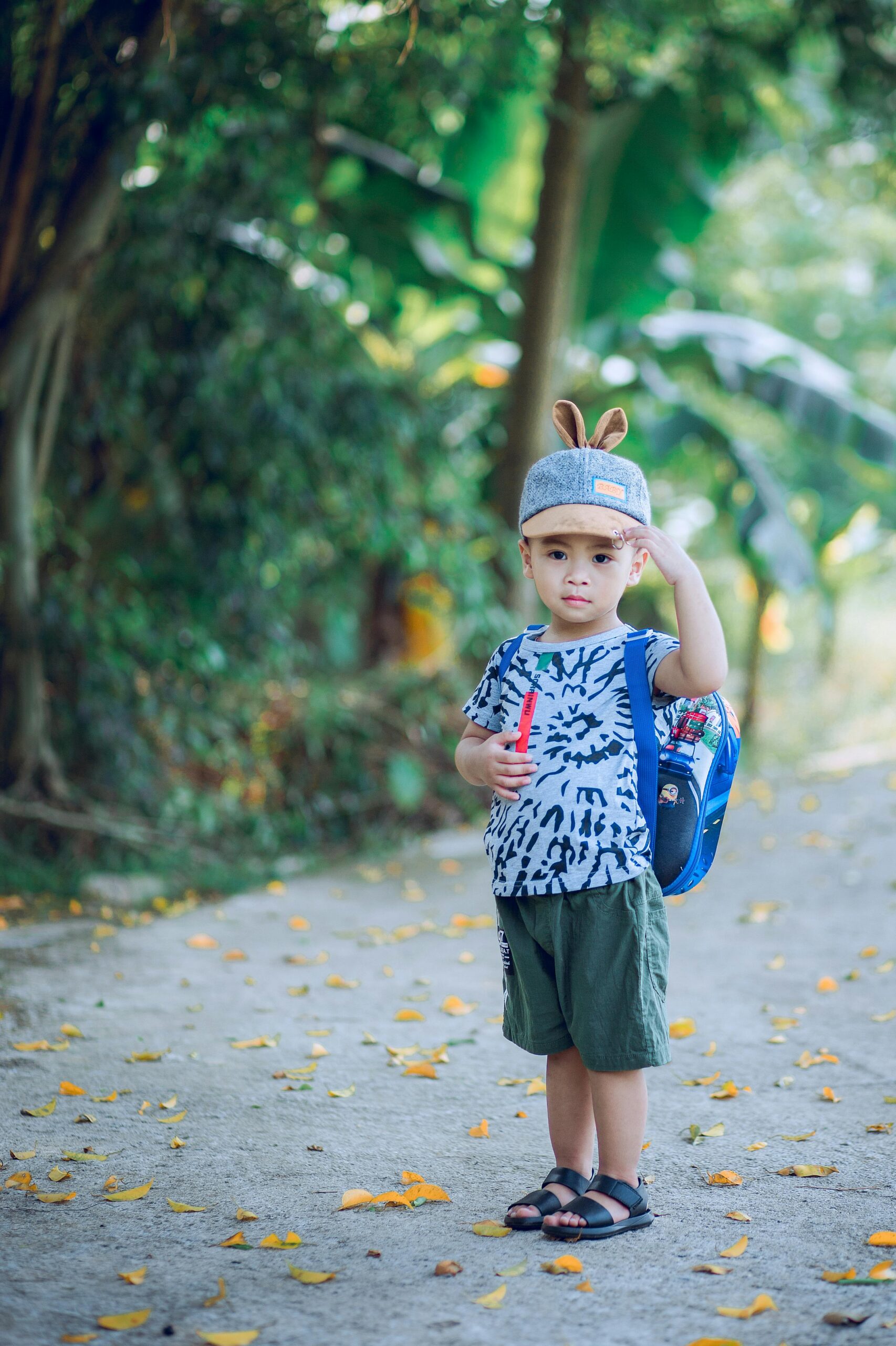 Adorable young boy with backpack enjoying a summer day outdoors, exuding joy and innocence.