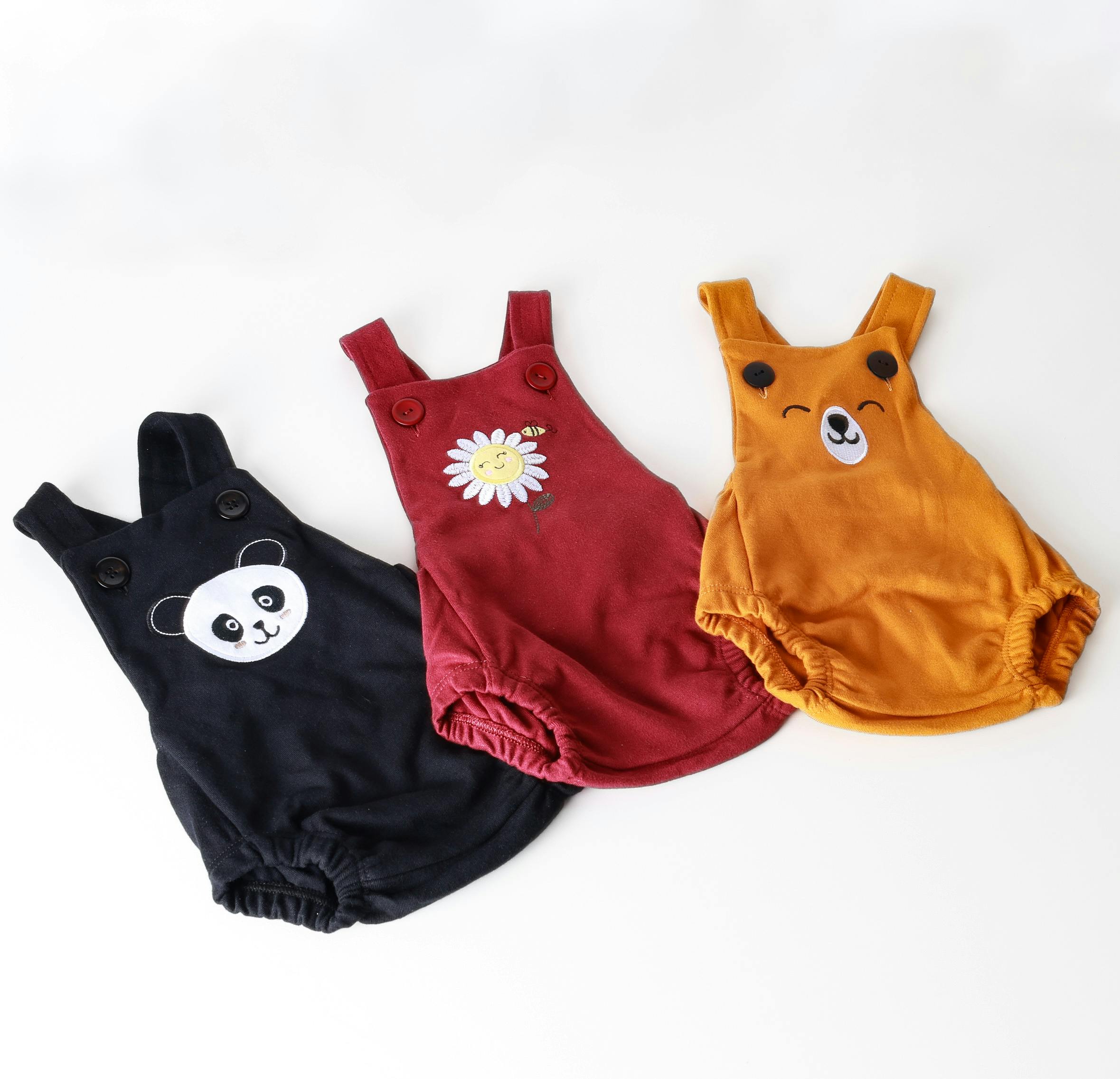 Set of three colorful baby onesies with adorable animal and flower designs on a white background.
