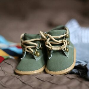 Adorable green baby booties surrounded by colorful clothes, perfect for infant fashion.